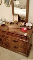Wood-tone dresser top with open hinged jewelry box, red round pouch, and scalloped display case in front of mirror