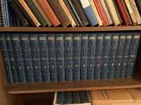 View of all 17 volumes lined up on a shelf, all with matching blue hardcover bindings and gold lettering on the spines.