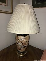 Full view of the table lamp with ceramic floral and bird design on base and fabric lampshade.