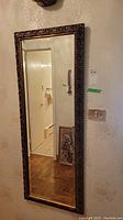 Full length view of the carved wood framed wall mirror showing its decorative edges and reflective surface.