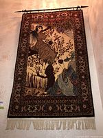 Full view of tapestry hung on wall from metal rod showing overall design and fringe.