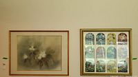 Photo showing original watercolor floral painting, close-up of flowers and leaves, gold frame and mat visible.