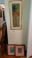 Three framed wall art pieces: one tall Asian floral print mounted on wall, two smaller floral prints below it.