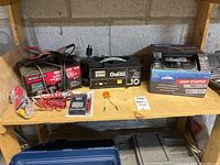 Shelf with Motomaster and Allanson battery chargers, small accessories, and boxed Peak jump starter