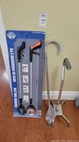 Full view of the lot showing two grabber tools in packaging, a folding cane, and a quad cane standing upright.