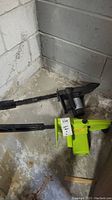 Two electric Mastercraft chainsaws on basement floor. One lime green, one black, both with 16-inch bars and chains.