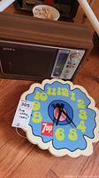 Photo showing the vintage Sony radio with wood grain finish and the vintage colorful 7up clock placed in front of it on a wood floor.