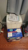 Whirlpool white dehumidifier unit with manual on top, Vicks vaporizer box in front.