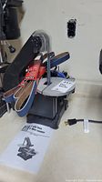 Overall view of the Power Fist 5 inch disc sander including sanding belts and user manual on a countertop.