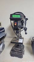 Front view of Jobmate drill press showing power switch, base, and work table with clamping vise