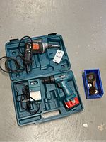 Full view of tools and accessories including Makita drill in case, charger, Black & Decker screwdriver, and wire brush attachments