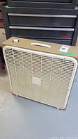 Side front view showing the box fan's exterior, rotary knob, and handle on top.