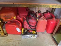 Shelf with multiple red and orange jerry cans and a box of pump accessories.