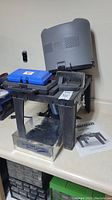 Full view of Ryobi router table with accessories including blue and black cases and dust collection hood. Includes Mastercraft manual on counter.