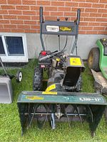 Front view of green and black Yardworks snow blower showing auger and chute