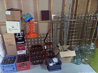 Overview of plastic buckets, crates of bottles, drying tree, corker, racks and demijohns