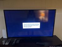 TV powered on showing cable provider message on screen, five remotes and a white cable modem/router on console