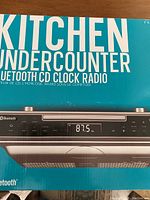 Front view of box showing kitchen undercounter Bluetooth CD clock radio brand new.