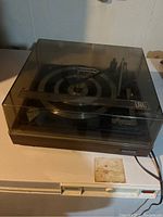 Side angle showing the Lloyds record player with dark tinted dust cover on, capturing overall condition and brand labeling.