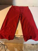 Front view of red Lululemon capri pants laid flat on white surface showing drawstring waistband.