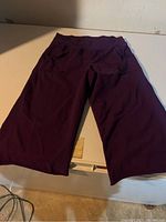 Front view of dark purple capri pants laid flat, showing overall condition and fit.