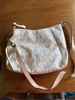 Front view of Michael Kors beige crossbody purse with MK monogram pattern, showing overall condition and leather strap.