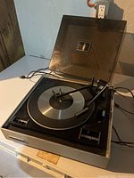 Vintage Panasonic record player with clear dust cover open, showing platter and tonearm.