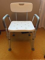 Front view of adjustable aluminum shower chair with white seat, backrest, and armrests.