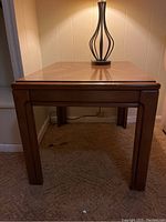 Front view of wooden side table with lamp base on top