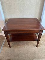 Full view of the small wooden coffee/side table showing the top surface with decorative edging and the legs.