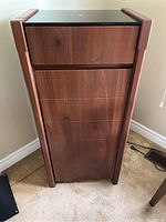 Front view of tall stereo cabinet with closed drawers showing wood grain and black top