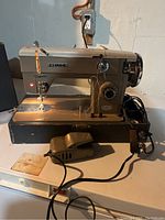 Vintage Nelco sewing machine powered on, showing controls, needle area, and foot pedal wired to machine