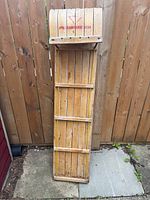 Top view showing the slatted wooden seat with red lettering, curved front slats, and wood frame.