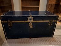 Front view of the navy blue vintage steamer trunk showing metal lock and clasps.