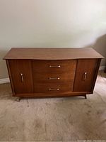 Front view of solid walnut buffet showing three central drawers and two side cabinets with metal handles.