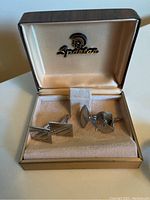 Two pairs of silver-tone cuff links in a beige velvet Spartan branded display box