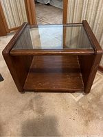 Side view of wood and glass side table showing scratches on bottom shelf and glass top panel