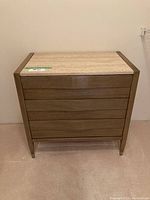 Front view of the American of Martinsville dresser showing three horizontal wood panel drawers and the light stone top.