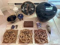 Overview of lot showing carved wood panels, Crown Devon vase, Noritake pieces, glass bird figurine, and other decorative items.