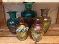 Five vases arranged on wooden shelf showing full set and relative sizes