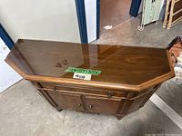 Top down angled view of the console showing the wood grain under a glass top and the overall shape and size of the piece.