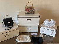 Overview photo showing all four white organizing boxes stacked and five vintage handbags arranged on and beside boxes.