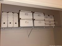 Photo showing the full set of 11 white organizing boxes on a wire shelf, including four magazine file holders, four square boxes, and three flat rectangular boxes.