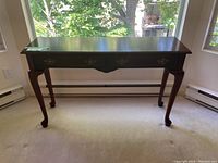 Front view of wood sideboard showing three drawers with brass handles and Queen Anne style legs.