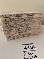 Stack of 12 small children's books by Beatrix Potter showing titles on spines clearly.