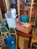 Wide shot showing brown textured sewing basket, white woven basket filled with yarn and knitting patterns, along with additional items like snowshoes and pens.