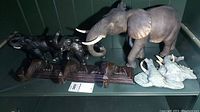 Display of multiple elephant figurines and the elephant coat hook on a shelf, showing detail and size variations.