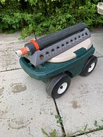 Close-up side view of Gardena Aquazoom 350/2 sprinkler mounted on wheeled garden seat.