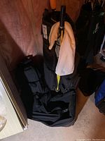Photo showing Bennington golf bag with two umbrellas inside it and a towel hanging on the top. Two black sports bags positioned next to the golf bag in basement setting.