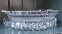 Close view of the two plates stacked and showing the decorative edge of the divided serving plate and the smooth edge of the pie plate